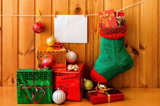 Calza di Natale, biglietto di auguri e regali contro muro di legno
 - Foto, immagini