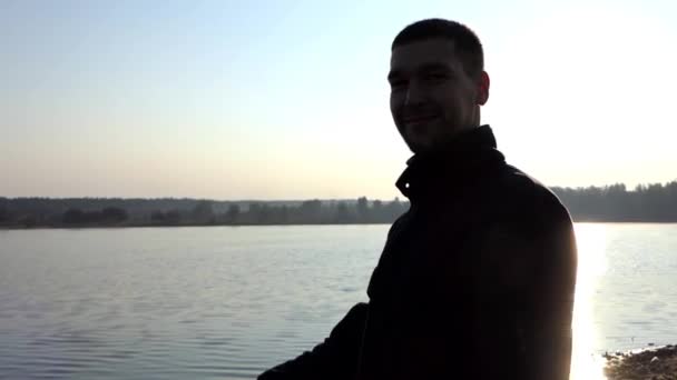 Young Dad Plays With an Infant Bodysuit on a Lake Bank at Sunset - Footage, Video