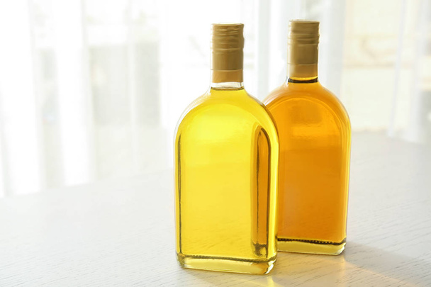 Bottles with oil on light wooden table - 写真・画像