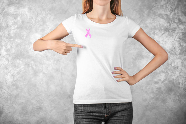Young woman with pink ribbon on color background. Breast cancer concept - Фото, зображення