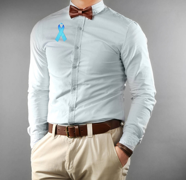 Young man with blue ribbon on gray background. Prostate cancer concept - Φωτογραφία, εικόνα