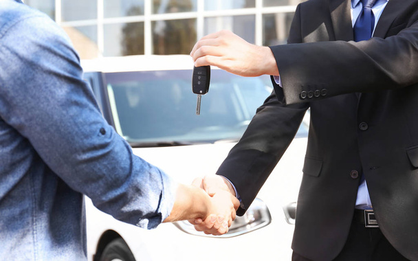 Salesman giving car key to customer outdoors - Fotoğraf, Görsel