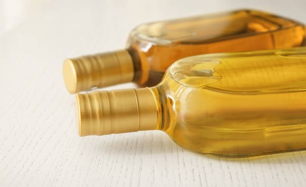 Bottles with oil on light wooden background - Fotografie, Obrázek
