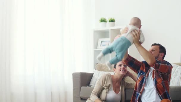 happy mother and father playing with baby at home - Materiał filmowy, wideo