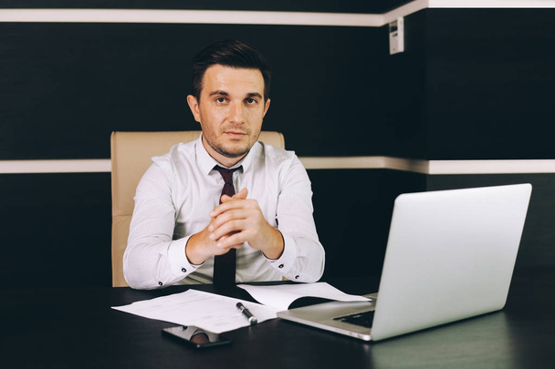 Attractive business man in smart casual wear sitting at his working place in office - Фото, зображення