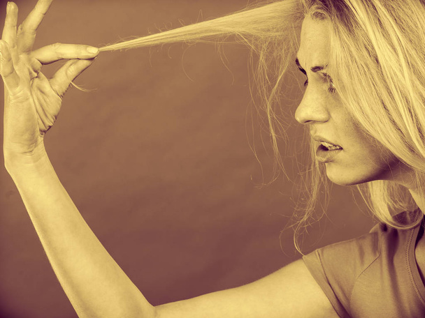 Sad woman looking at damaged hair ends - Foto, Imagem