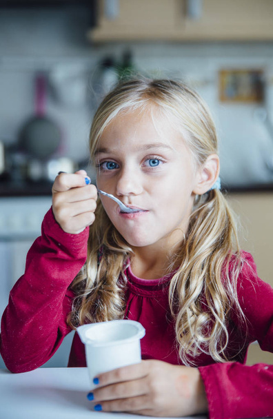 Little girl eating a healthy yoghurt breakfast - Fotó, kép