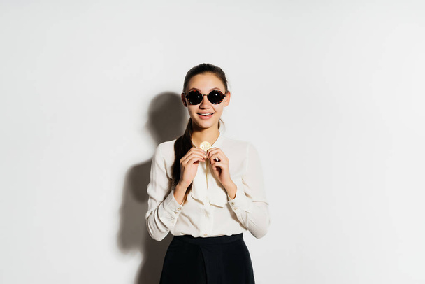 a girl in a white shirt and wearing round sunglasses is holding coins. Bitcoins, crypto currency, electronic money - Foto, immagini