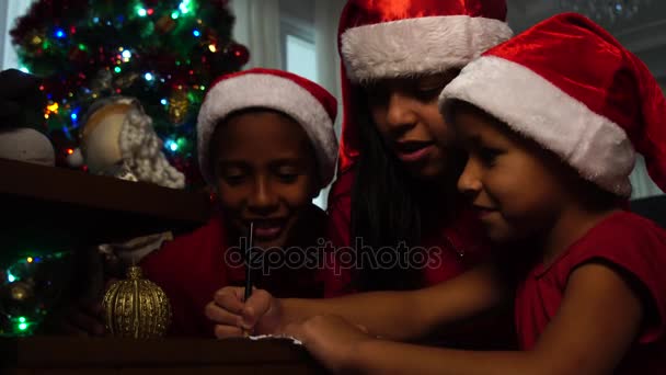 Niña escribiendo una carta de Navidad a Santa Claus con su familia
 - Imágenes, Vídeo