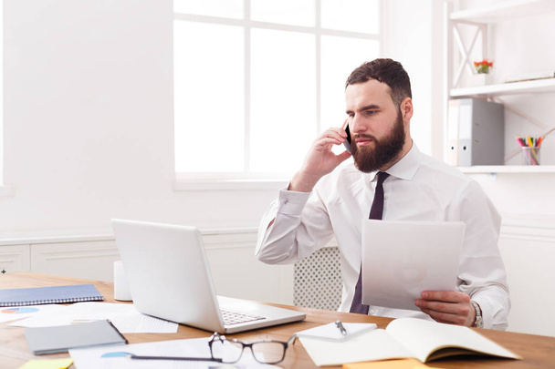 Seriöser Geschäftsmann mit Laptop im modernen weißen Büro - Foto, Bild