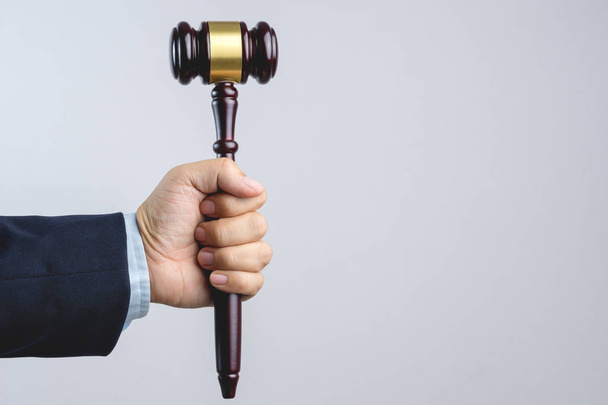 白い背景の法律や正義の記号として木製の裁判官の小槌を持っているビジネス男手 - 写真・画像