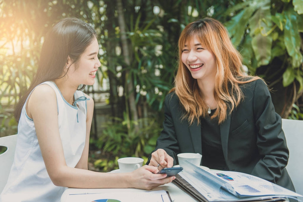 Twee vrouwelijke ondernemers bespreken over grafische papierwerk op tafel. - Foto, afbeelding