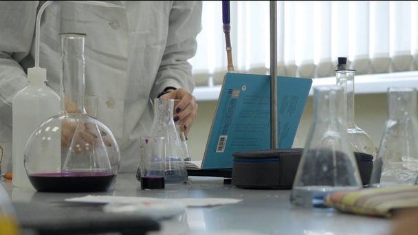 ラボのテクニシャンで実験を行うラボで。男性の医学か科学的な実験室の研究者は、青色の液体とテストを行います。科学者は実験室でフラスコを使用 - 写真・画像