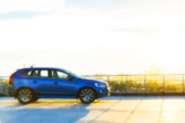 Blurred background with modern luxury car on the blur roof of the building at the sunset. Modern car exterior details. Soft lightning  - Foto, Bild