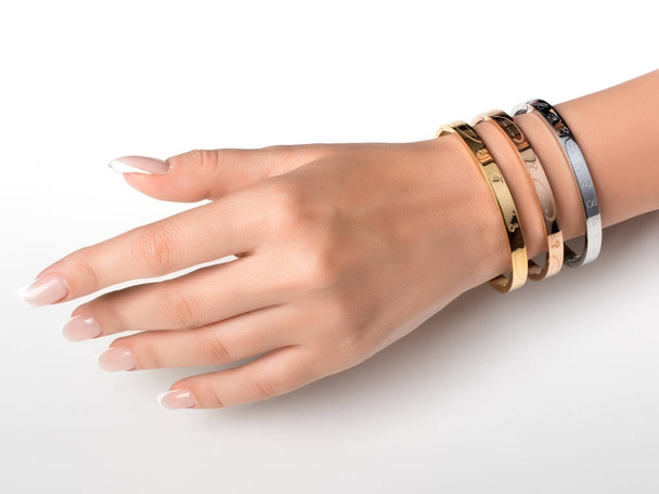 Bracelet set on a hand with French manicure, jewelry on a model - Фото, зображення