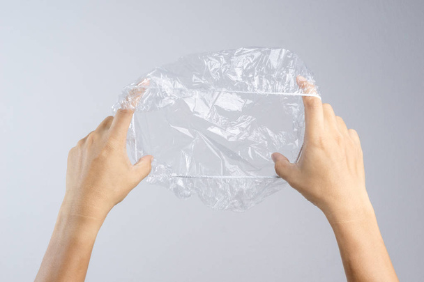 Hand holding disposable transparent plastic shower cap on white background - Photo, Image