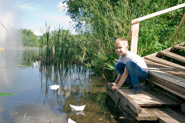 A boy with a paper boat by the river.  - Foto, Imagen