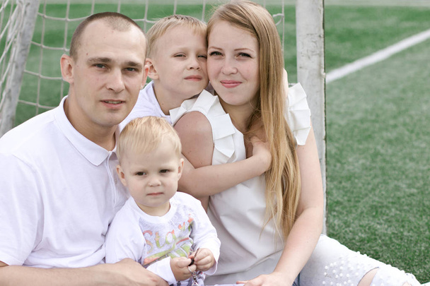 A family of four on a football field. Bright sunny summer day. - Valokuva, kuva