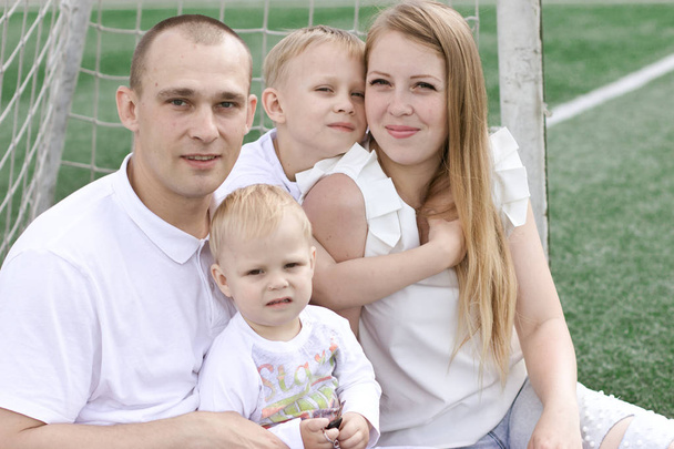A family of four on a football field. Bright sunny summer day. - Foto, Bild