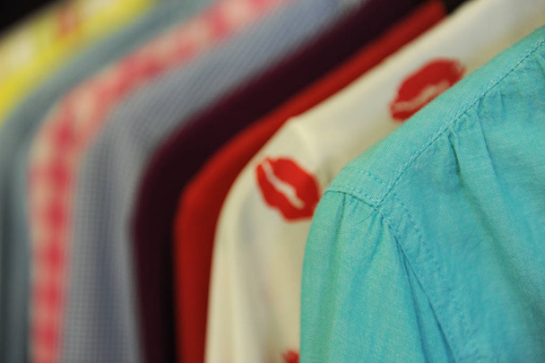 Υφή φόντου από μια σειρά από χρωματισμένα πουκάμισα και μπλούζες σε μια κρεμάστρα - Φωτογραφία, εικόνα