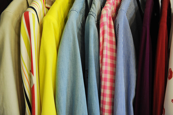 Textura de fondo de una fila de camisas y blusas de colores en una percha
 - Foto, imagen