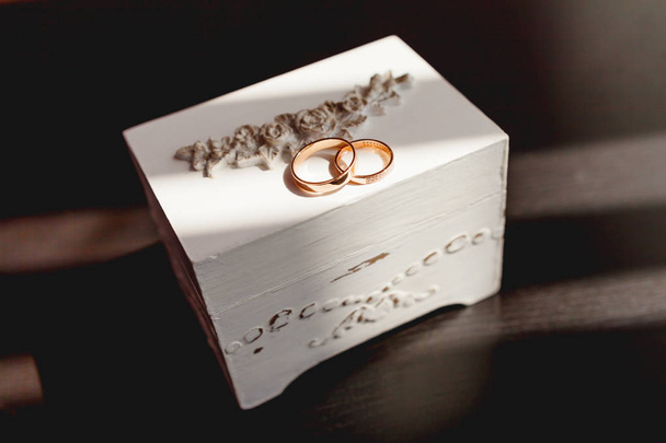 Paire d'anneaux de mariage dorés avec diamants sur boîte décorative blanche minable. Beau symbole d'amour et de mariage
. - Photo, image