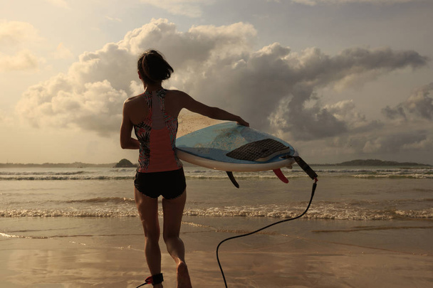 young surfer with surfboard walking to sea  - Foto, Imagen