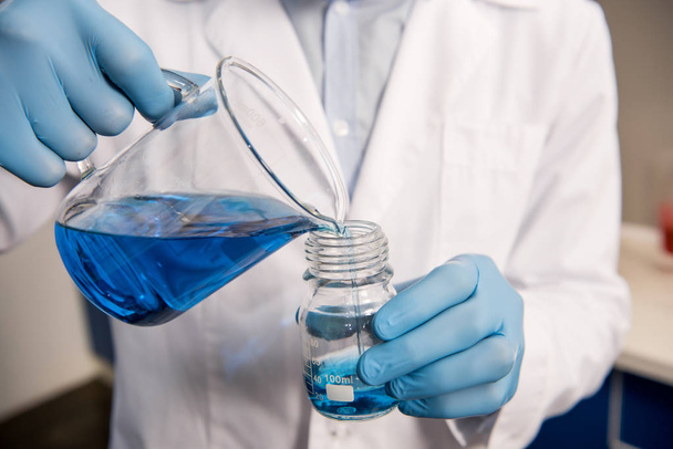 scientist pouring reagent into jar - Foto, Imagem