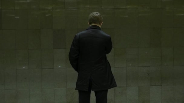 Eenzame jonge man van achter bij metrostation. Jonge man wacht op een trein in de metro, achteraanzicht - Video