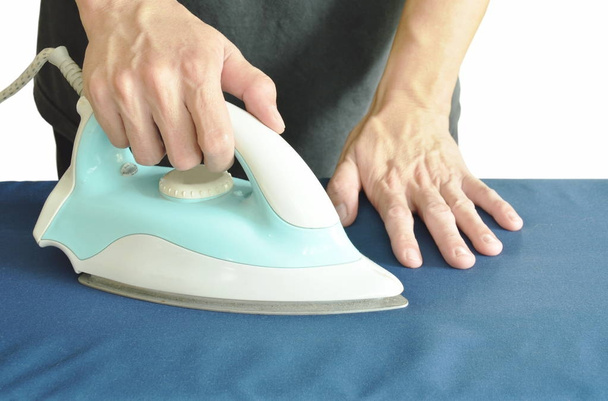 man pressing blue automatic electric iron to shirt on ironing board - Φωτογραφία, εικόνα