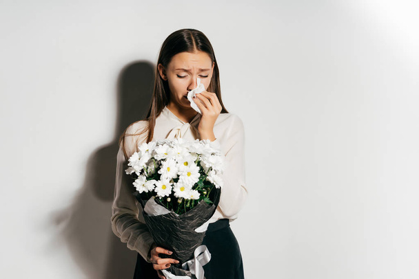 young beautiful happy girl holding a big bouquet of white flowers and sneezing because she is allergic - Foto, Bild