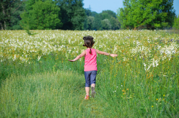 Child on green spring meadow, kid running and having fun outdoors - Photo, image