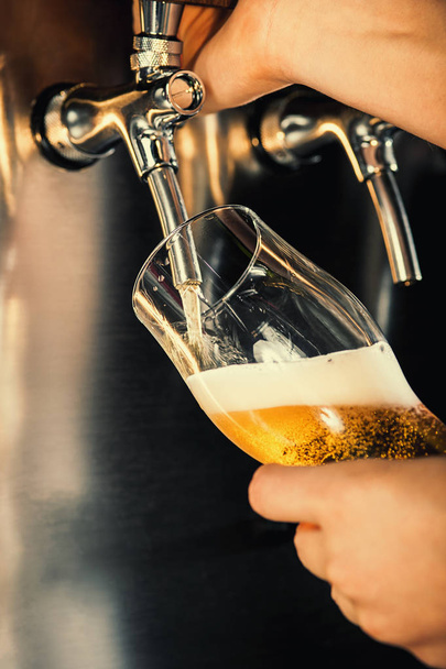 ręka barman leje duże piwo lager w kran. - Zdjęcie, obraz
