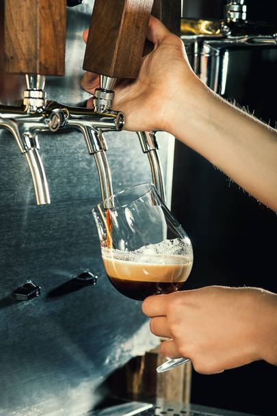 Hand of bartender pouring a large lager beer in tap. - Fotoğraf, Görsel