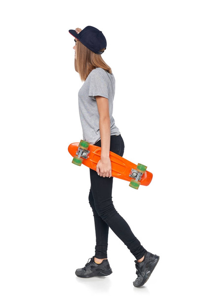 Back view teen girl in full length with skate board - Фото, изображение