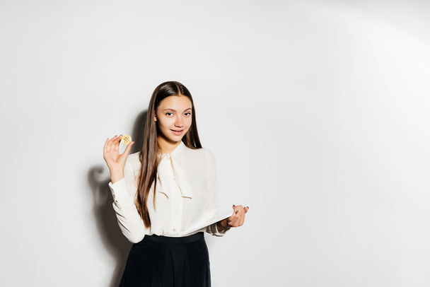 young successful modern girl holding a gold bitcoin and a tablet in her hand - 写真・画像