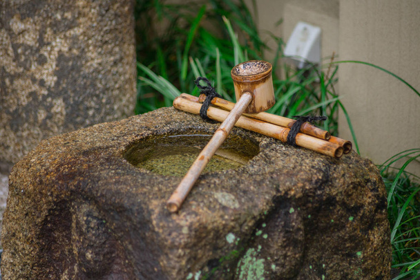 Tsukubai Ιαπωνία πέτρα νερού νιπτήρα με μπαμπού κουταλιά νερό για τον καθαρισμό επισκέπτες. - Φωτογραφία, εικόνα