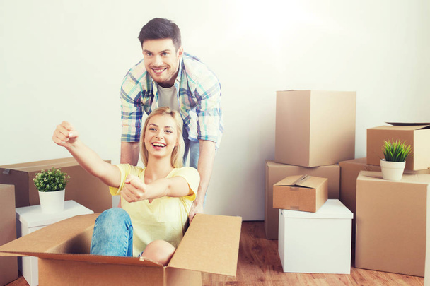happy couple having fun with boxes at new home - Фото, изображение