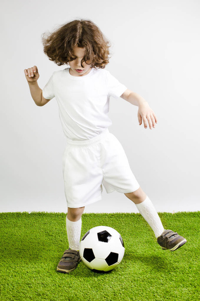 Young football player playing soccer on the grass. Gray background. - Foto, afbeelding