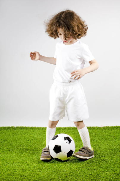 Young football player playing soccer on the grass. Gray background. - Valokuva, kuva