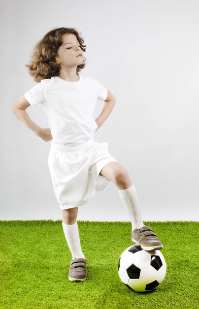 Young football player playing soccer on the grass. Gray background. - Foto, immagini