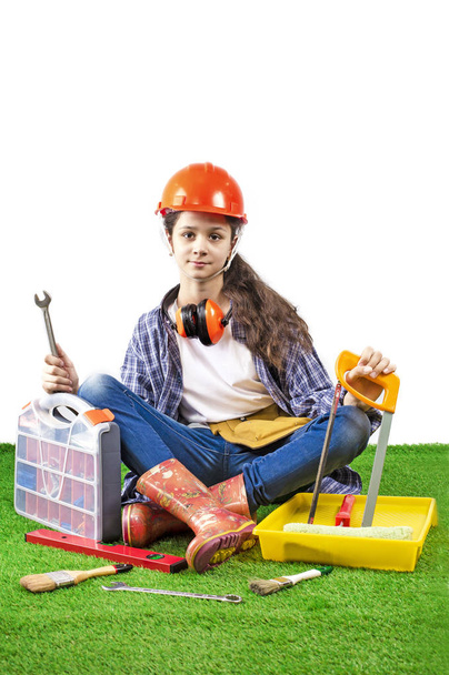 Girl builder holding a construction tools sitting on the grass - Foto, Bild