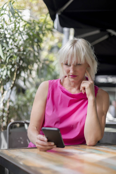 Zralá blondýna žena používající mobilní telefon venku - Fotografie, Obrázek