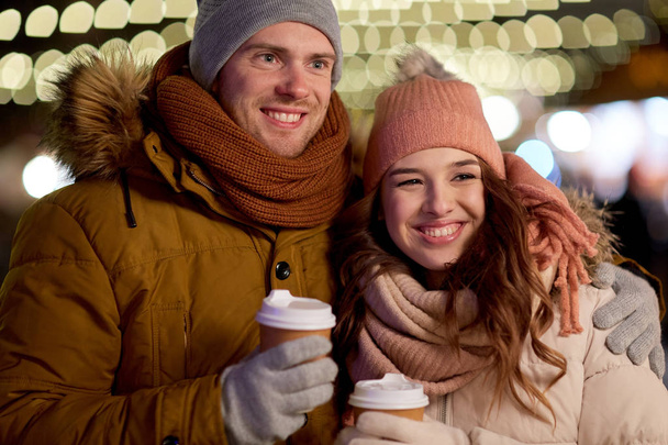 happy couple with coffee over christmas lights - Photo, image