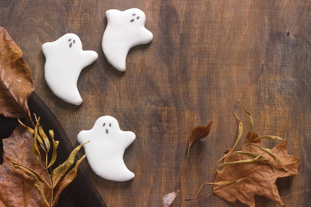 Perníková ghost pro halloween, zdobené s podzimním listím, na dřevěné pozadí. - Fotografie, Obrázek