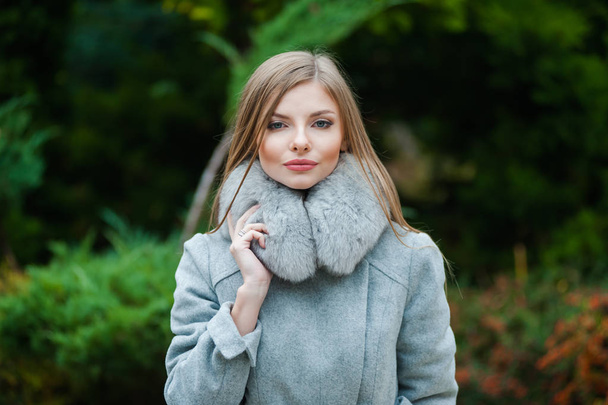 秋の毛皮のコートを身に着けている美しい若いブロンドの女性 - 写真・画像