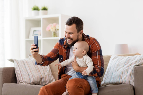 happy father with baby boy taking selfie at home - Zdjęcie, obraz