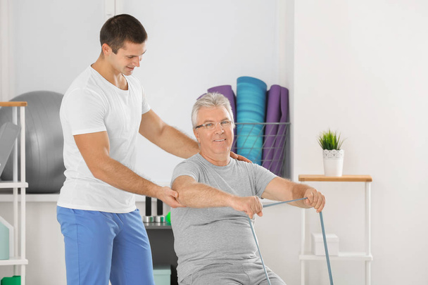 Physiotherapist working with senior patient in modern clinic - Zdjęcie, obraz