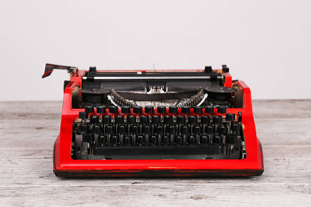 The typewriter is red with paper in it and on the table - Foto, Bild