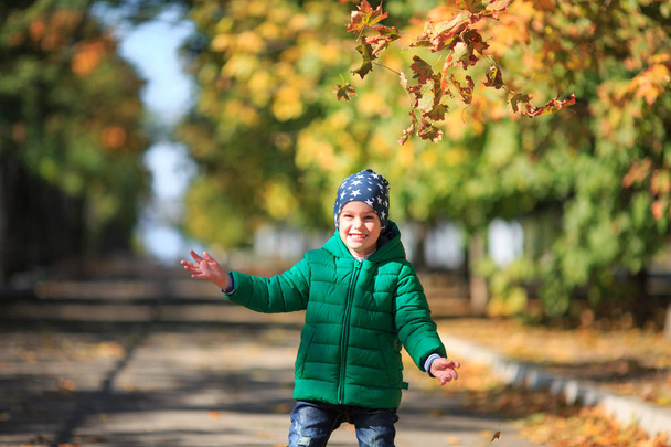 A boy plays in the autumn on the street - Фото, изображение